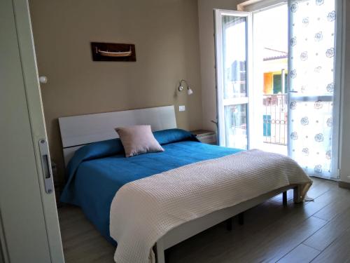 a bedroom with a bed with a blue blanket and a window at Danilo Apartments in Baveno