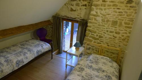 a bedroom with two beds and a stone wall at Gite Bleu in MÃ©nil-Vin