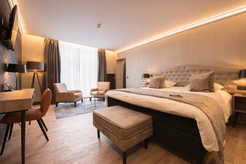 a hotel room with a large bed and a desk at Hotel Acacia in Bruges