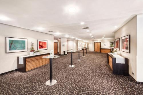 a hallway with a row of tables and paintings on the walls at Clayton Hotel Düsseldorf City Centre in Düsseldorf