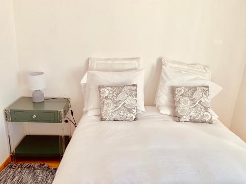 a bed with white sheets and pillows and a night stand at Apartments Alfacinha Ajuda in Lisbon