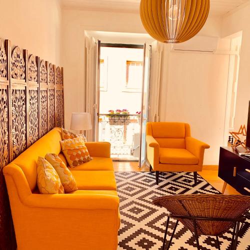 a living room with a yellow couch and two orange chairs at Apartments Alfacinha Ajuda in Lisbon