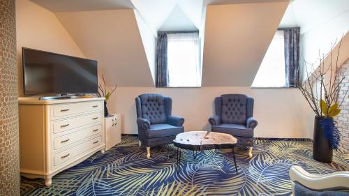 a living room with two blue chairs and a tv at ART Hotel in Sibiu