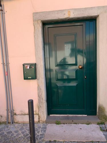 a green door of a building with a man sitting at it at Apartments Alfacinha Ajuda in Lisbon
