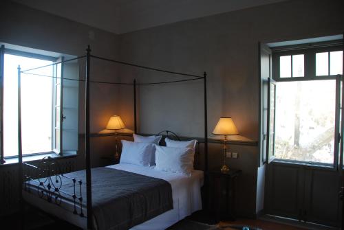a bedroom with a canopy bed with two windows at Hotel L'Iglesia in El Jadida