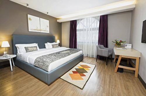 um quarto de hotel com uma cama, uma secretária e uma cadeira em San Cristobal Boutique Hotel - Ivato Airport em Antananarivo