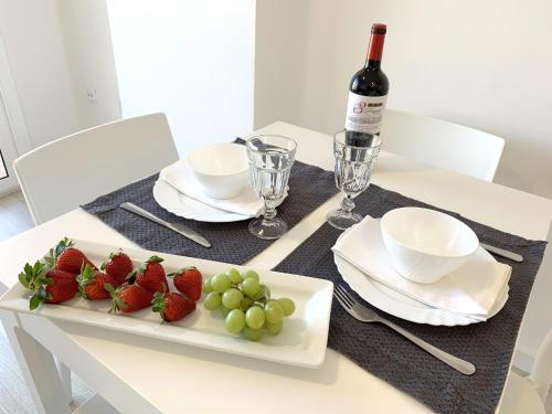 a table with strawberries and grapes and a bottle of wine at Apartamento 1ª Linea de Mar -WIFI- Aire Acondicionado in Empuriabrava
