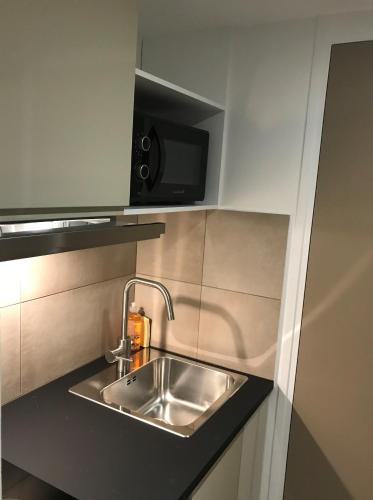 une cuisine avec un évier et un micro-ondes dans l'établissement AMHotel Italie, à Paris