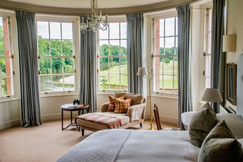 um quarto com uma cama, uma cadeira e janelas em Warwick Hall em Carlisle