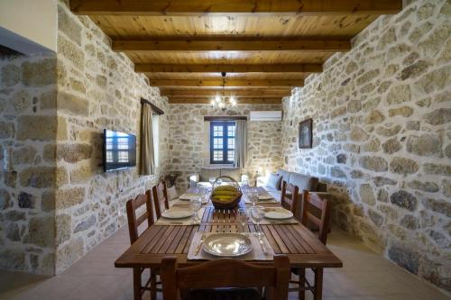 a dining room with a wooden table and a stone wall at Villa Kaladare - Private Pool & Quiet Relaxing Stay in Kalandares