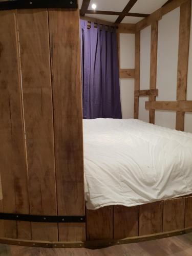 a bedroom with a bed and a purple curtain at Le Coeur De La Foret in Pierrefonds