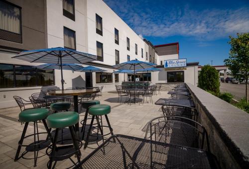 an outdoor patio with tables and chairs and umbrellas at Holiday Inn & Suites Syracuse Airport - Liverpool by IHG in Liverpool