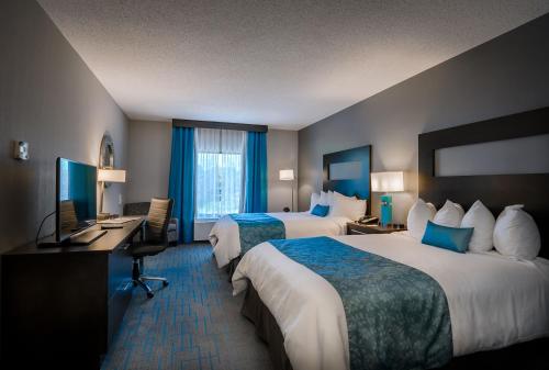 a hotel room with two beds and a desk at Holiday Inn & Suites Syracuse Airport - Liverpool by IHG in Liverpool