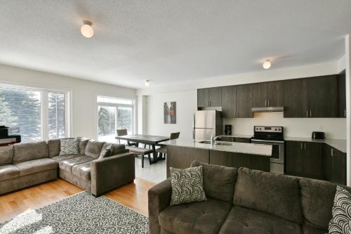 a kitchen and living room with couches and a table at New Blue Mountain Village Snowbridge Executive Townhome Sleeps 10 with Outdoor Pool and Shuttle in Nottawa