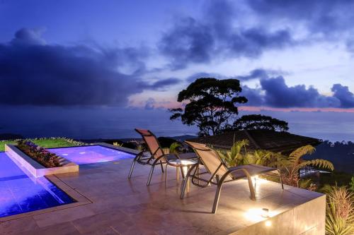 a patio with chairs and a swimming pool at night at Rancho Pacifico - Boutique Hotel for Adults in Uvita