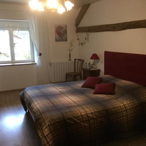 une chambre avec un lit avec deux oreillers rouges dessus dans l'établissement Le Chanois, à Fontaine