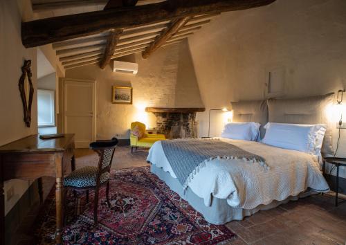 a bedroom with a bed and a desk and a fireplace at Ca' Bianca Tuscany Relais in Siena