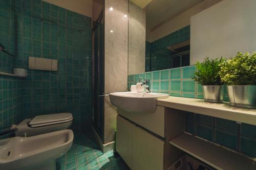 een badkamer met een wastafel, een toilet en groene tegels bij Accogliente monolocale alla Gran Madre in Turijn