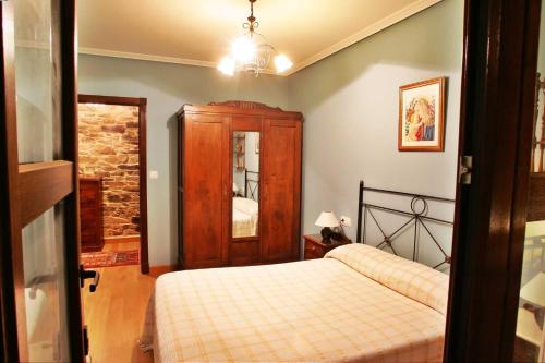 a bedroom with a bed and a wooden cabinet at Palleira de Roque in Bermés