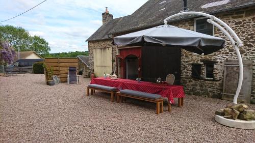 a table with a red table cloth and an umbrella at Gite Rouge and la Ferme Blanche in MÃ©nil-Vin