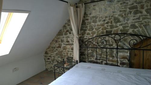 a bed in a room with a stone wall at Gite Rouge and la Ferme Blanche in MÃ©nil-Vin