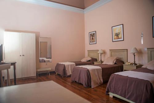 a hotel room with three beds and a television at Posada del Frayle Bentos in Fray Bentos