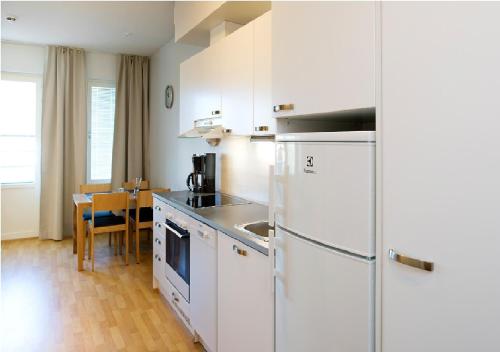 a kitchen with a white refrigerator and a table at Cozy Central Studio Tampere in Tampere