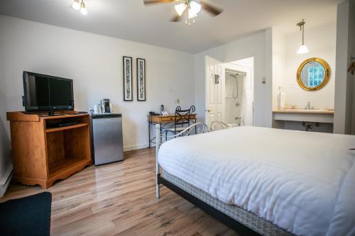 a bedroom with a bed and a flat screen tv at Auberge Seigneurie des Monts in Sainte-Anne-des-Monts