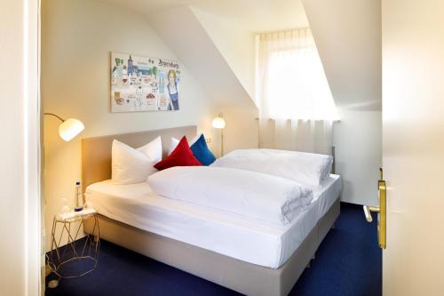 a bedroom with a white bed and white walls at Hotel Rosi in Regensburg