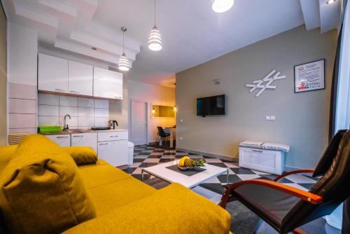 ein Wohnzimmer mit einem gelben Sofa und eine Küche in der Unterkunft Apartman Luka in Livno