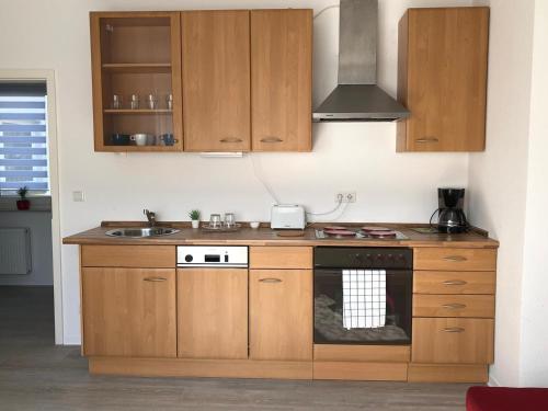 a kitchen with wooden cabinets and a stove top oven at Helle Ferienwohnung an der Rheinpromenade 50 qm in Duisburg