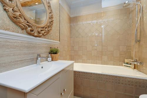 une salle de bain avec un lavabo, une baignoire et un miroir dans l'établissement Dzirnavu Residense, à Riga