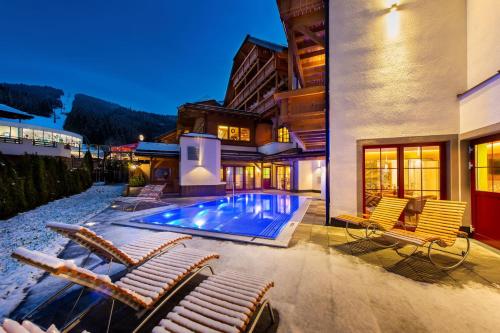 una casa con piscina y tumbonas en Grizzly Sport & Motorrad Resort, en Sankt Margarethen im Lungau