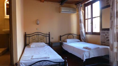 a bedroom with two beds and a window at Kydonia Rooms in Chania