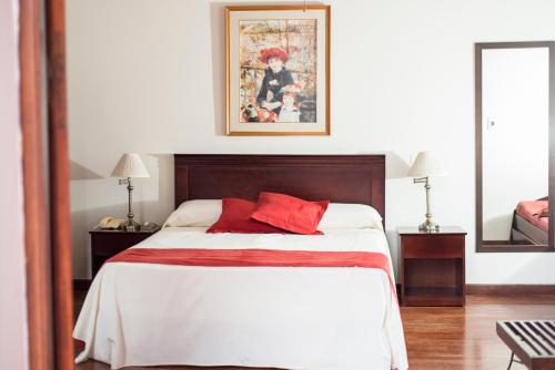 a bedroom with a large bed with red pillows at Posada del Frayle Bentos in Fray Bentos