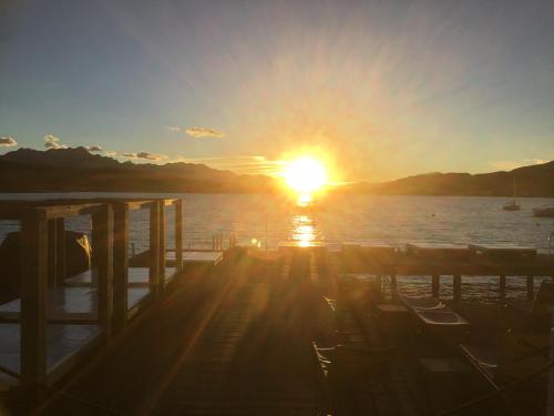 a sunset over the water with chairs on a pier at Villa Auguste in Pörtschach am Wörthersee