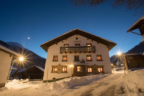 a large building in the snow at night at Pension der Steinbock - das 300 Jahre alte Bauernhaus - TIROL in Sankt Anton am Arlberg