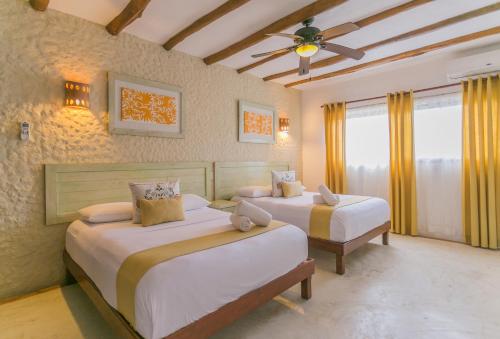 a bedroom with two beds and a ceiling fan at Villas Margaritas Holbox in Holbox Island