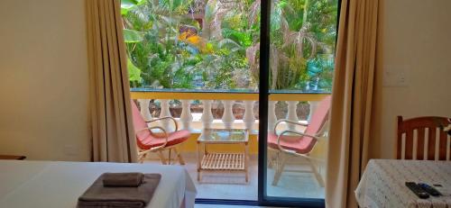 a room with a view of a balcony with chairs at Primavera Holiday Homes-FAMILY RUN GOAN GUEST HOUSE in Candolim