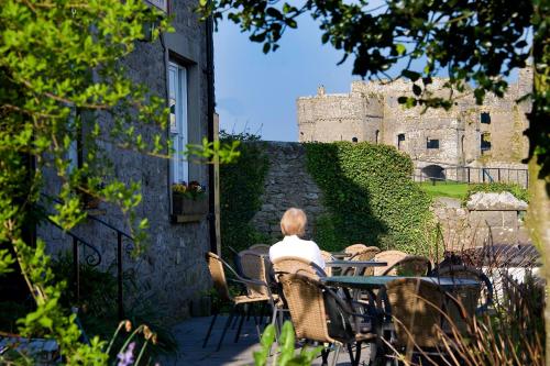 een vrouw aan een tafel voor een kasteel bij Carew Inn in Tenby