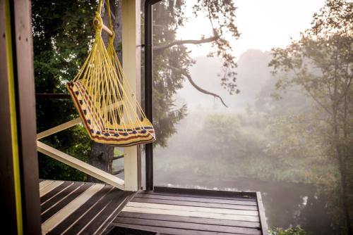 a hammock hanging from a window on a porch at VIP Yellow dream house Sodyba Geras geltona žalia raudona violetinė in Anykščiai