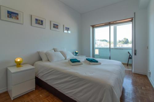 a white bedroom with a large bed with two towels on it at Cacilhas Amazing view of Lisbon close to beach Caparica in Almada