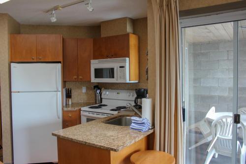 a kitchen with a white refrigerator and a sink at Pacific Shores Resort & Spa in Nanoose Bay