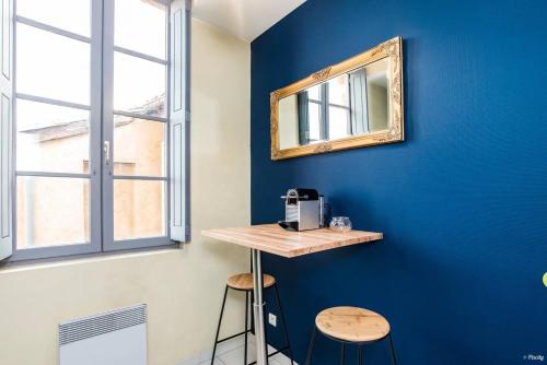 un espejo en una pared azul con una mesa y taburetes en Appartement Le Paon en Toulouse