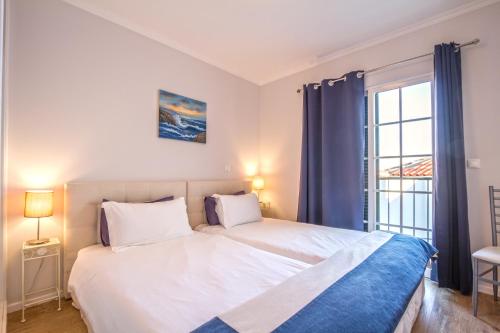 a bedroom with a large white bed and a window at Old Town House Madeira in Funchal