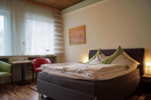 a bedroom with a bed and a chair and a window at Hotel-Cafe Maxx in Lengerich