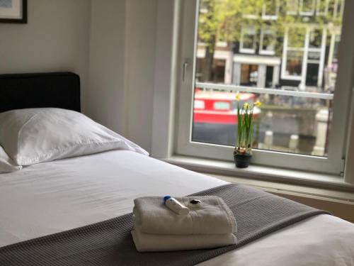 ein Bett mit einem Handtuch darauf mit einem Fenster in der Unterkunft Bridge Inn in Amsterdam