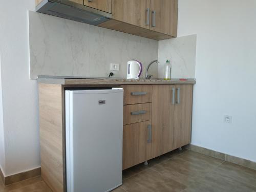 a kitchen with wooden cabinets and a white refrigerator at Alise in Bar