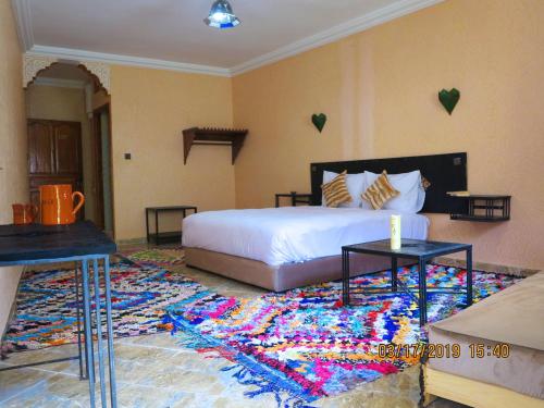 a bedroom with a large white bed and a colorful rug at Kasbah Imoula in Imlil