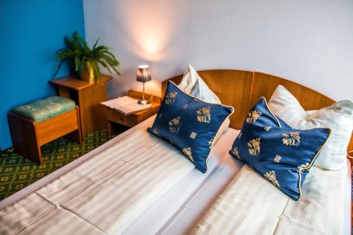 1 dormitorio con 1 cama con almohadas azules y blancas en Kompleks Noclegowo-Gastronomiczny Laguna, en Niewiesze